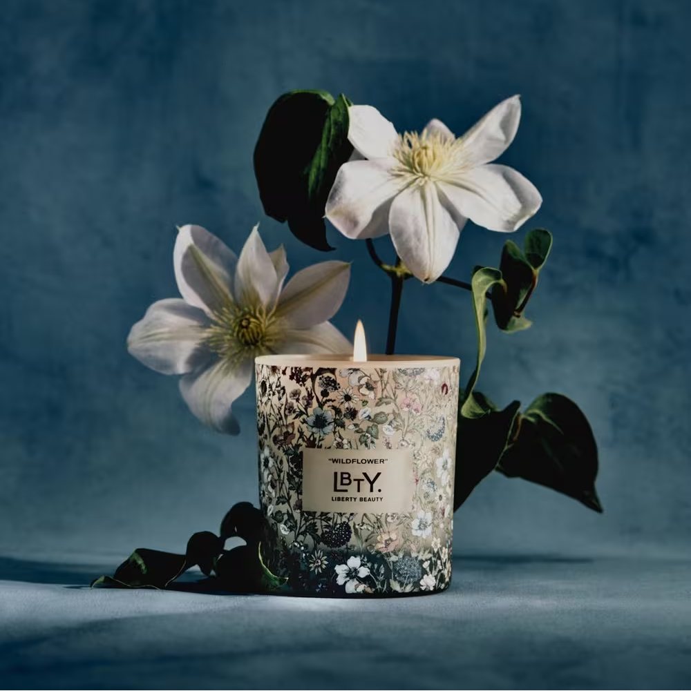 Candle with floral design in a decorative container on a blue background