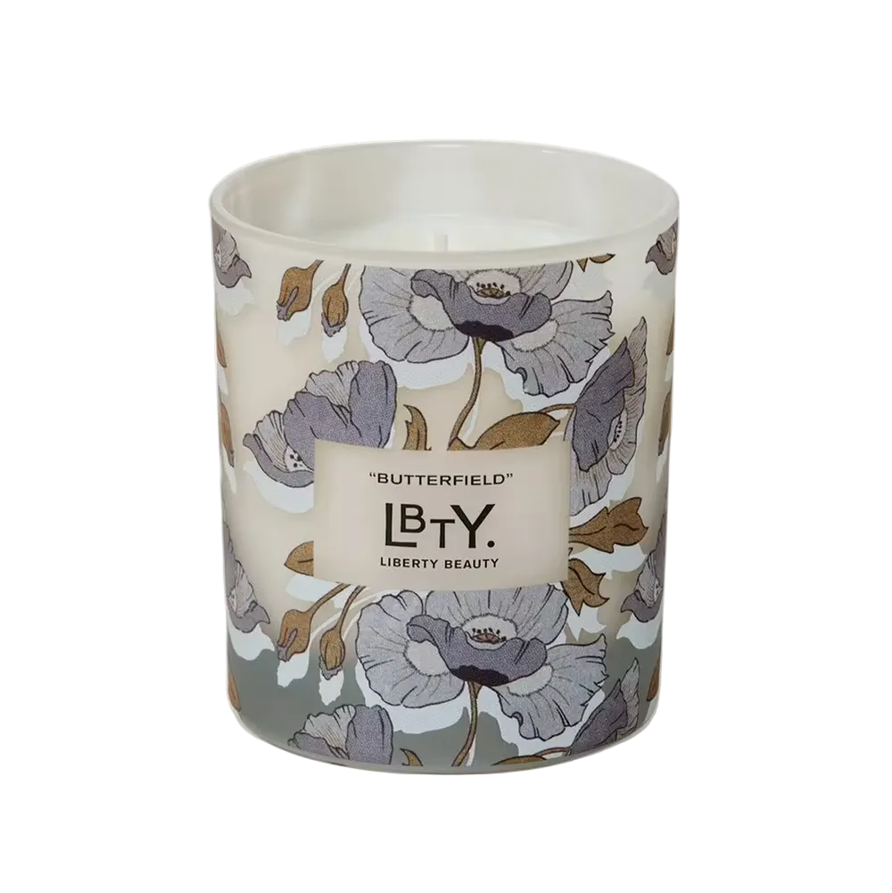 Candle with floral design and 'LBTY' branding on a white background