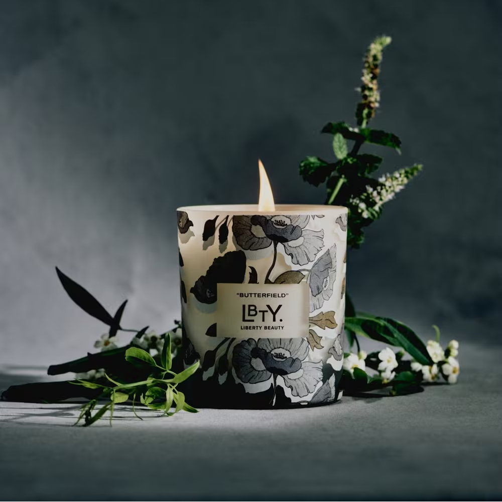 Floral-patterned candle with 'LBTY' branding on a dark background