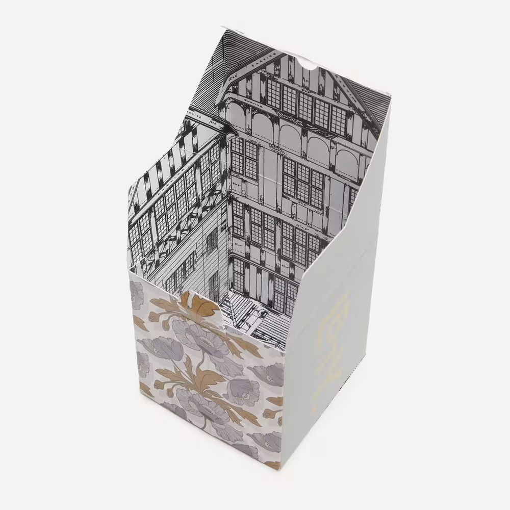 Cardboard box with architectural design on one side and floral pattern on the other, on a white background.