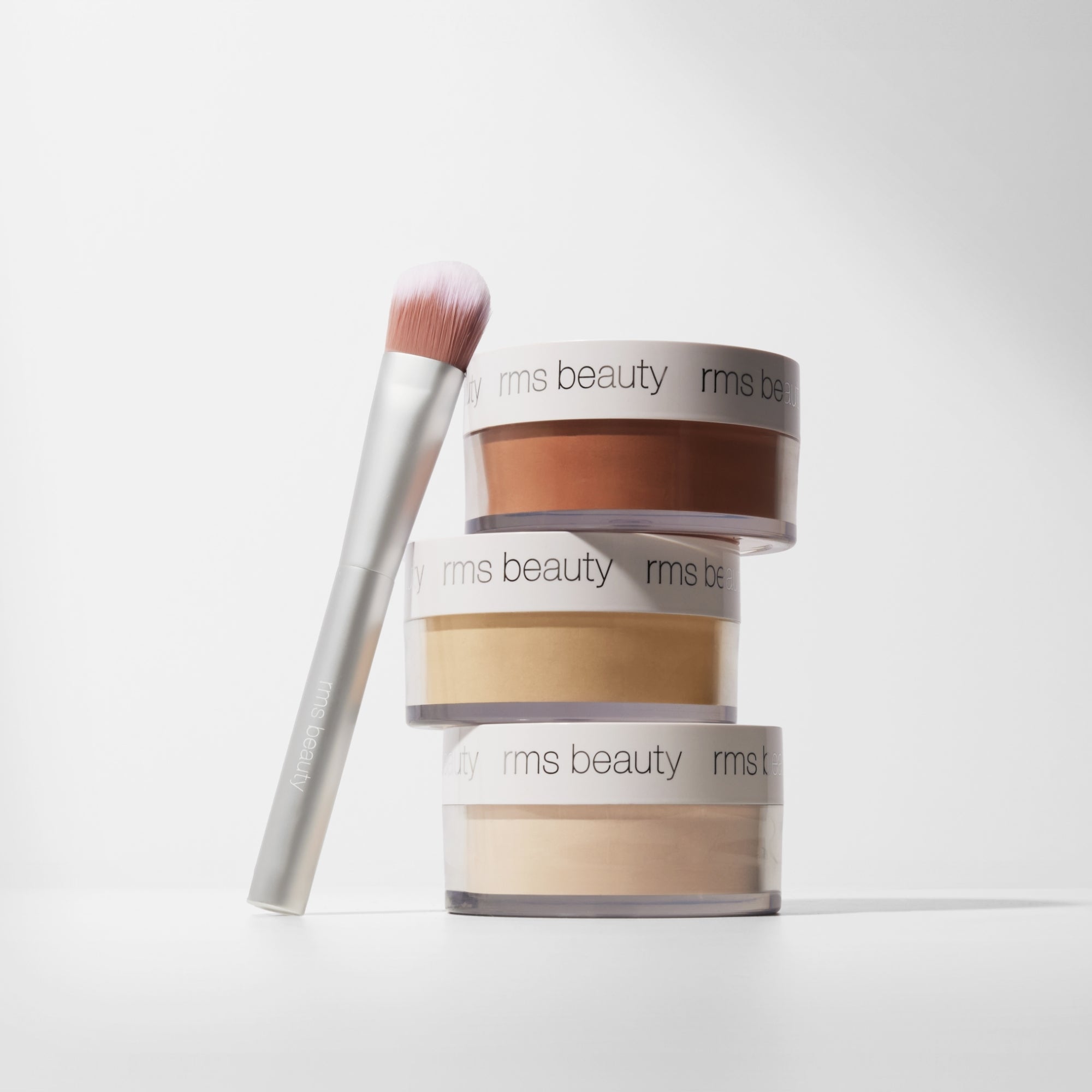 RMS Beauty makeup products with a brush on a white background