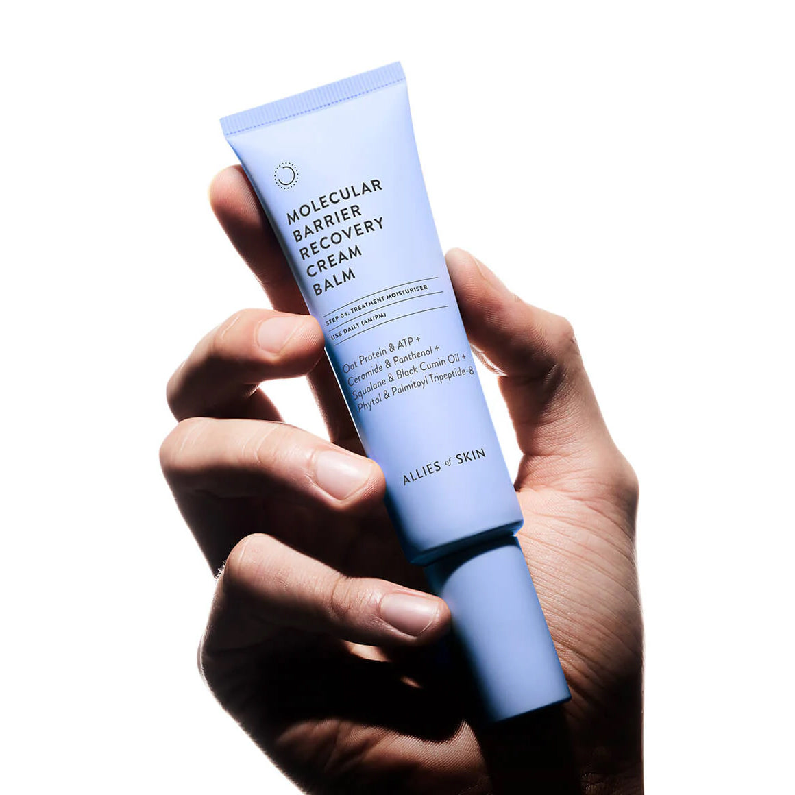 Hand holding a tube of 'Molecular Barrier Recovery Cream Balm' by Allies & Skin on a white background