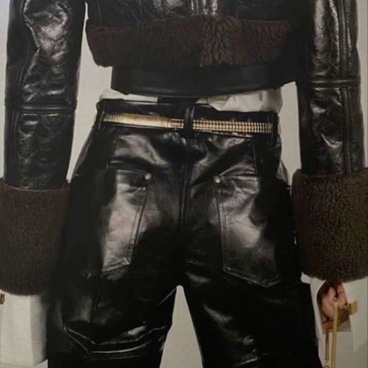 Person wearing a black leather jacket and pants on a plain background