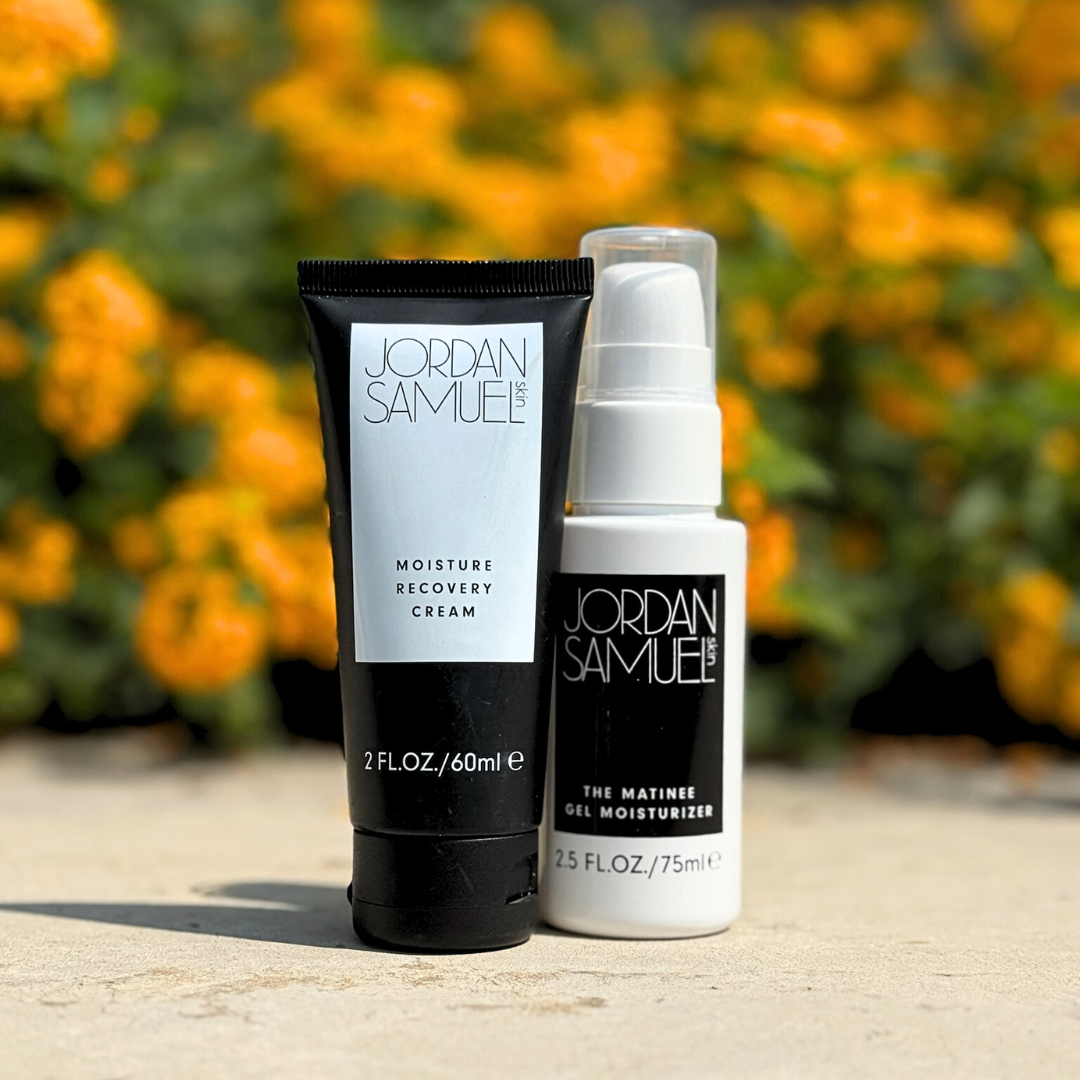 Two skincare products from Jordan Samuel on a stone surface with a blurred floral background.