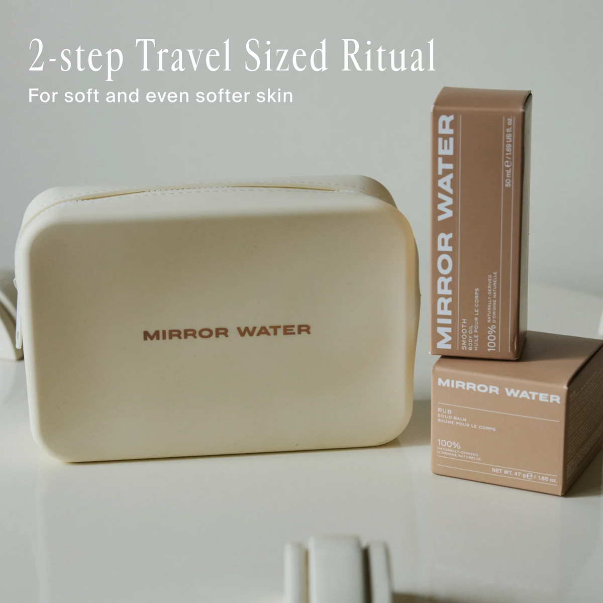 A cream-colored makeup bag with 'MIRROR WATER' printed on the front, shown next to two brown boxes of the same brand on a white surface. Text at the top reads '2-step Travel Sized Ritual For soft and even softer skin'.
