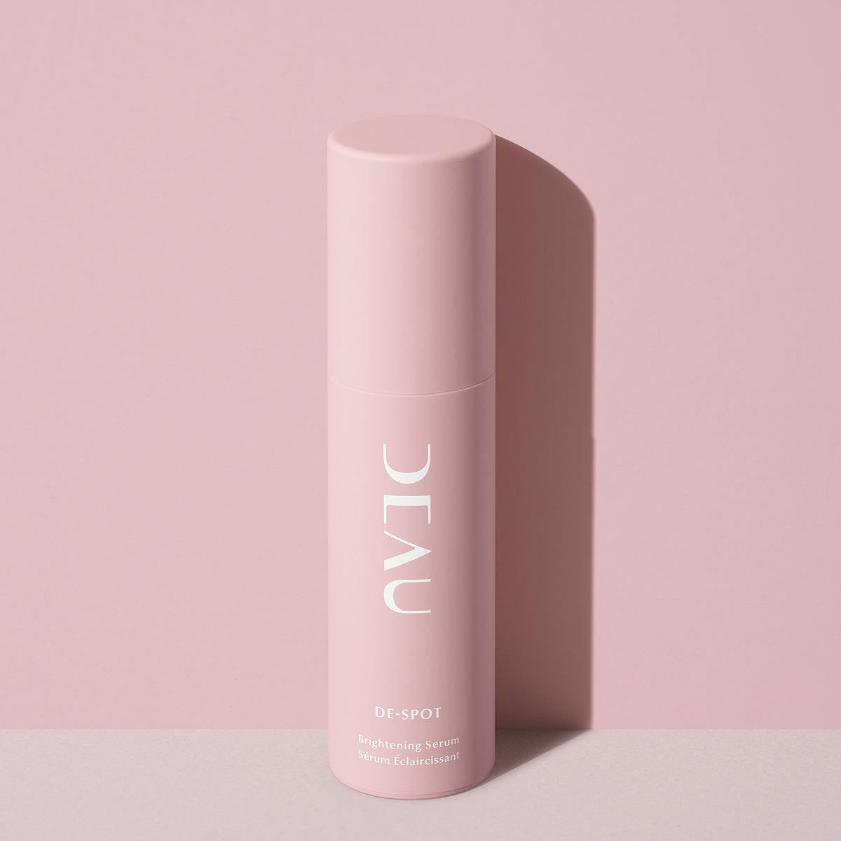 Pink skincare bottle labeled 'DEAU' on a pink background