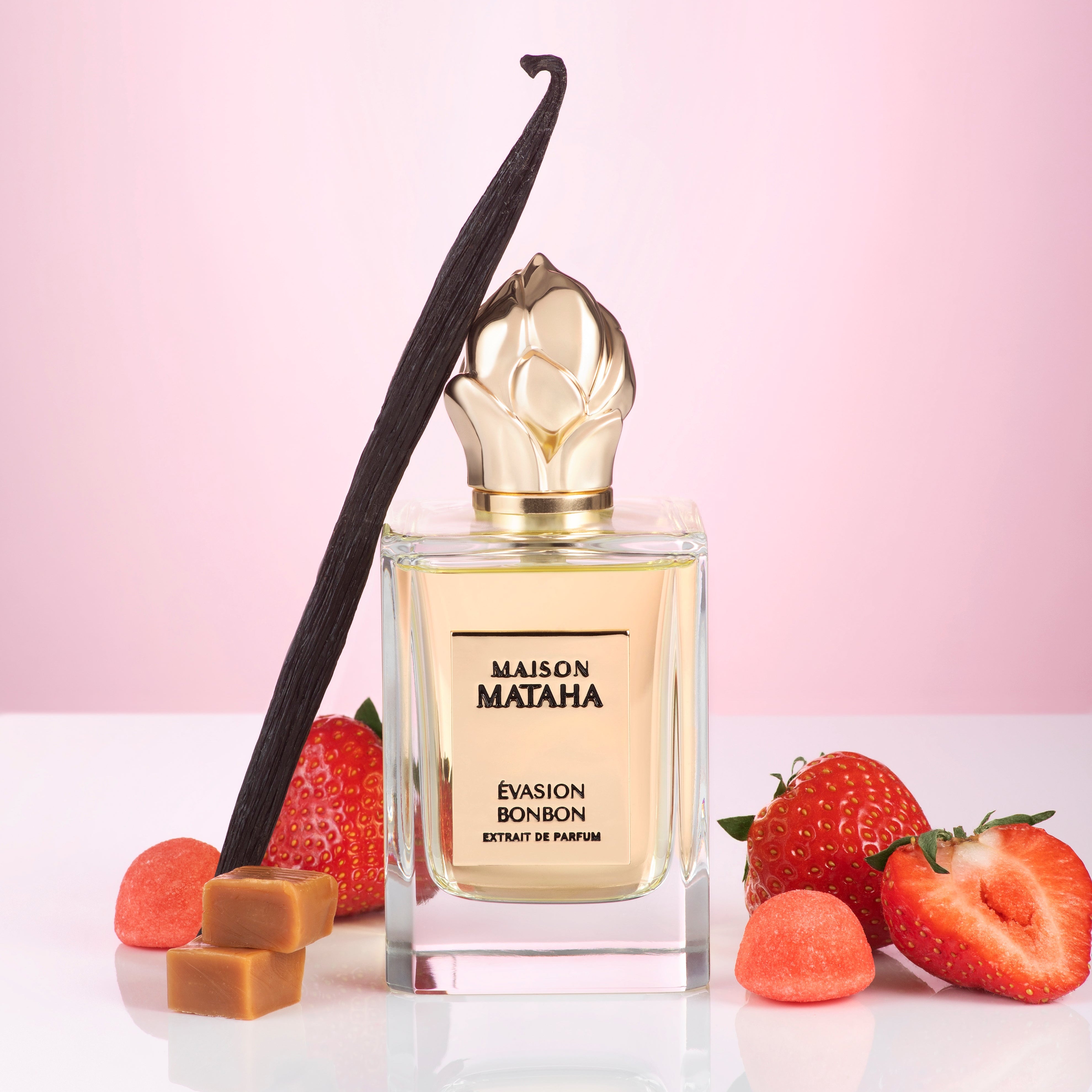 Maison Mataha perfume bottle surrounded by strawberries, vanilla and caramel on a pink background