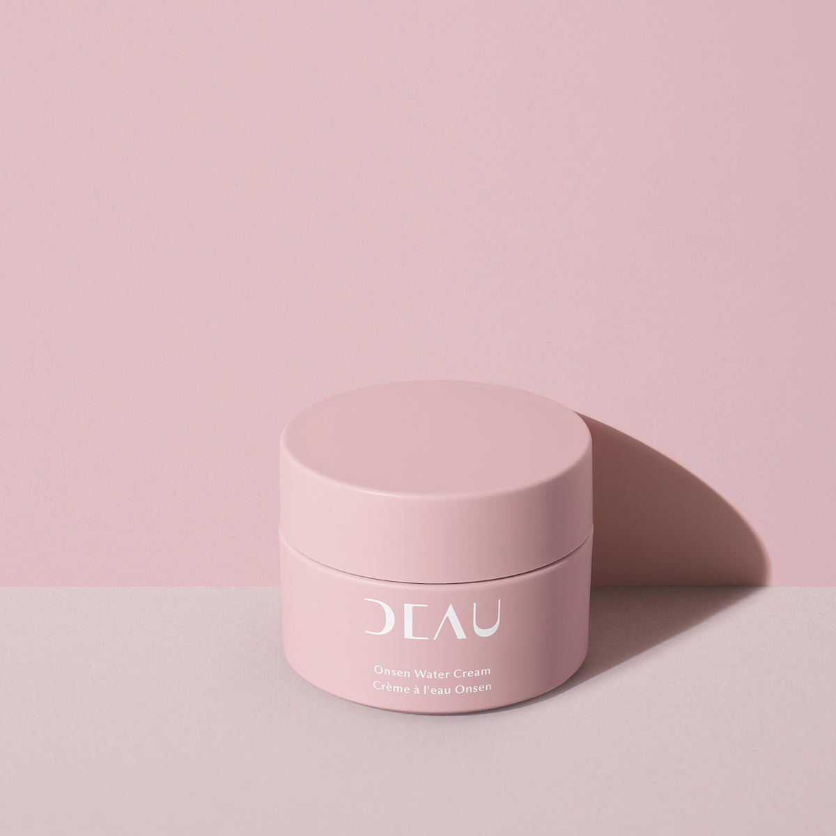 Pink jar of cream with 'DEAU' branding on a pink background