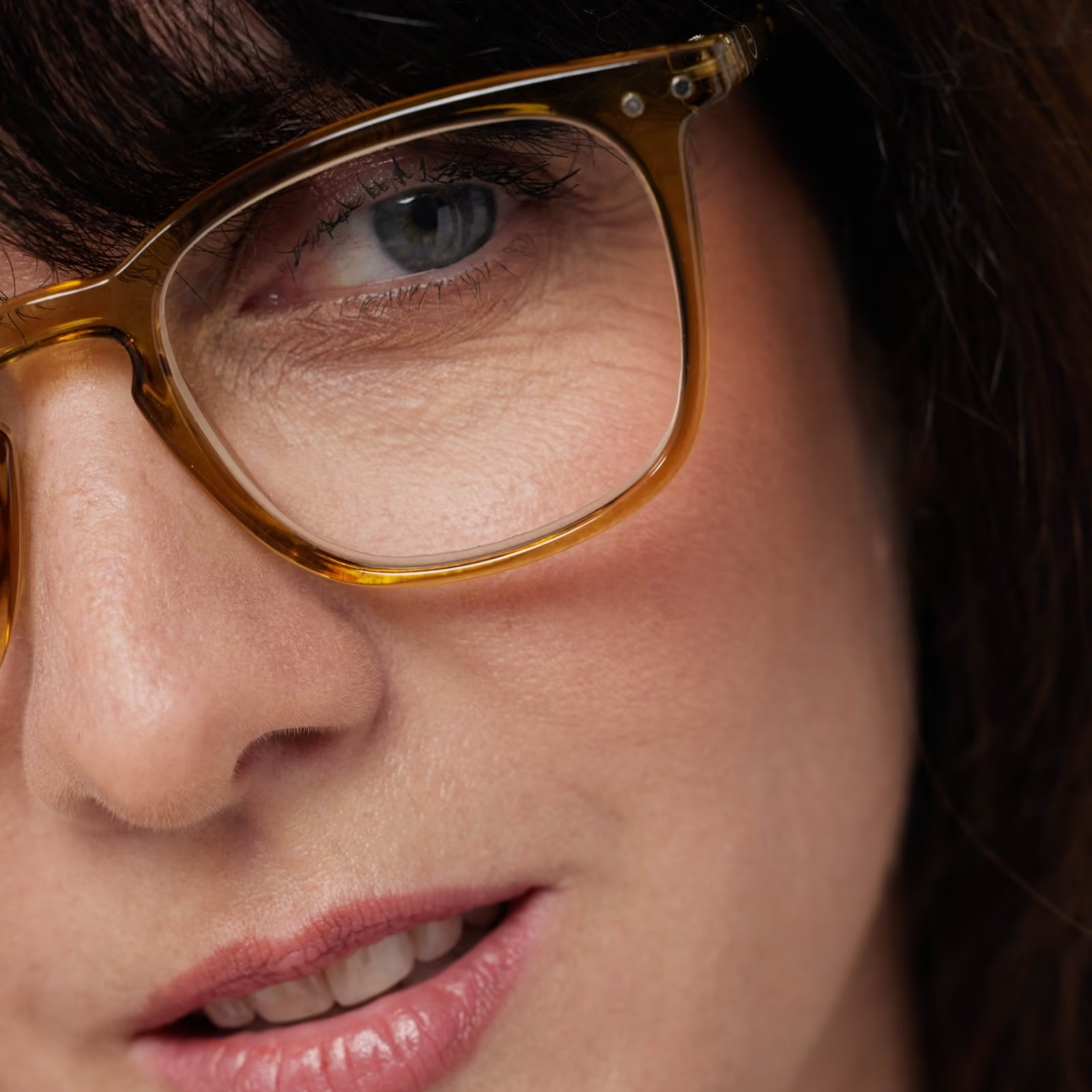 Close-up of a person wearing golden green-framed glasses with a blurred background