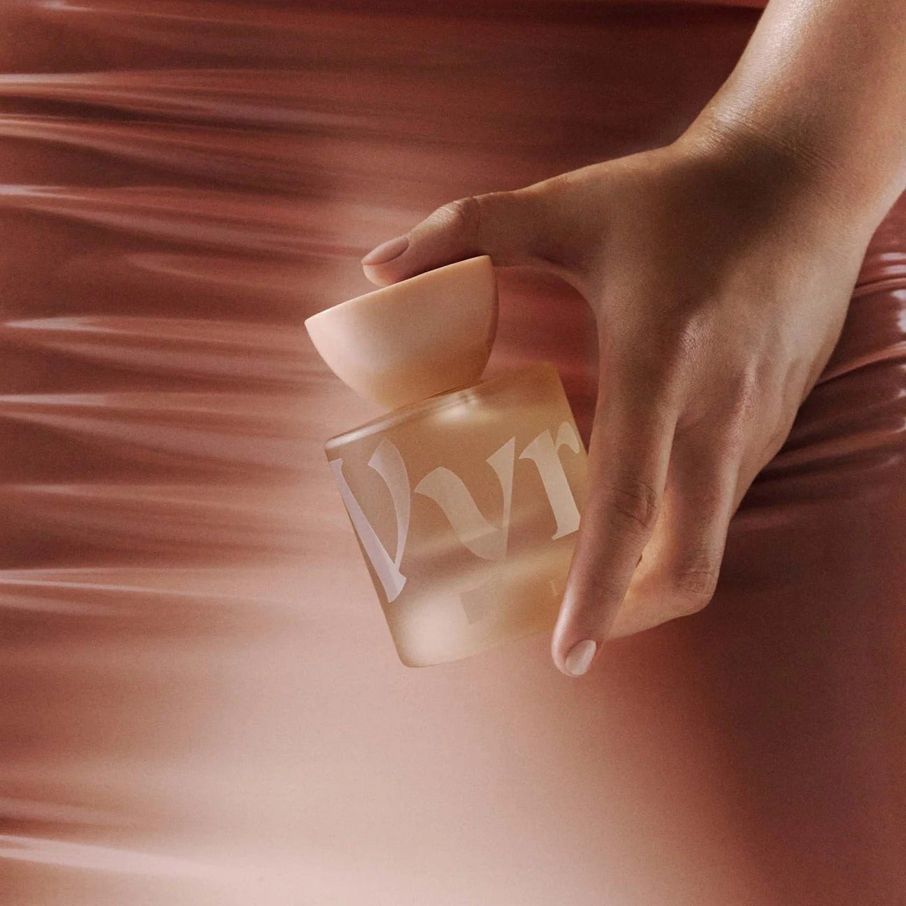 Hand holding a glass bottle with a blurred background.