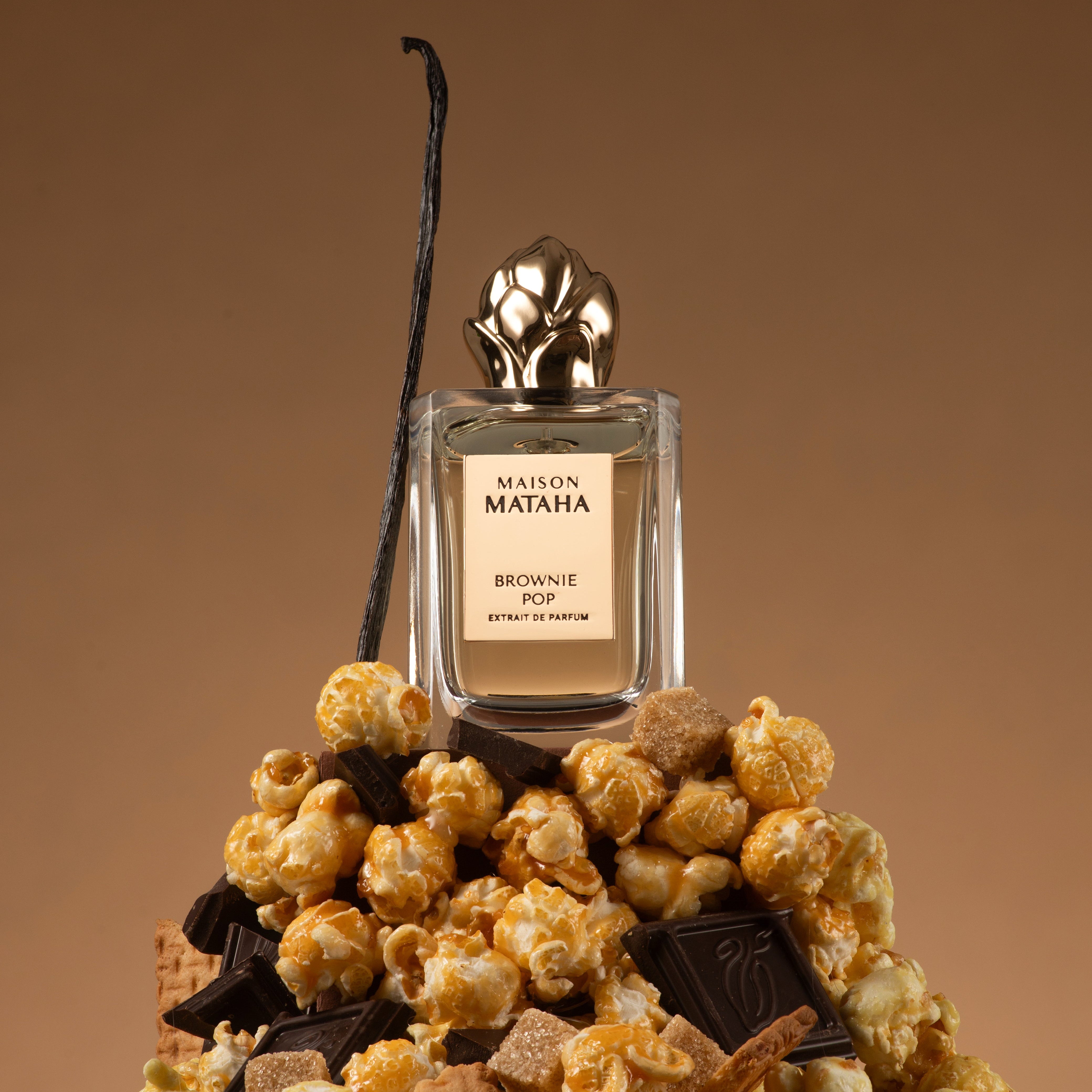 Maison Mataha perfume on a stack of chocolate, hazelnuts, and caramel corn