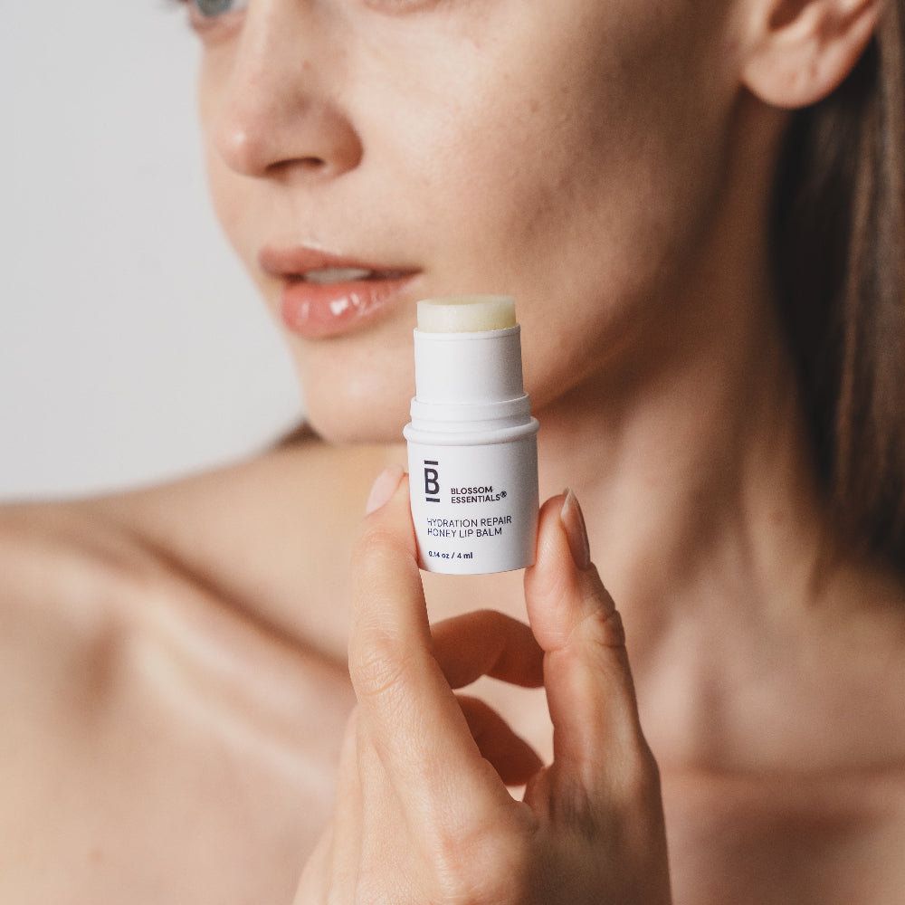 Woman holding a skincare product close to her face against a neutral background