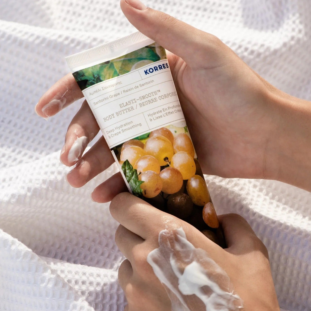 Hand holding a Korres body butter with a white background