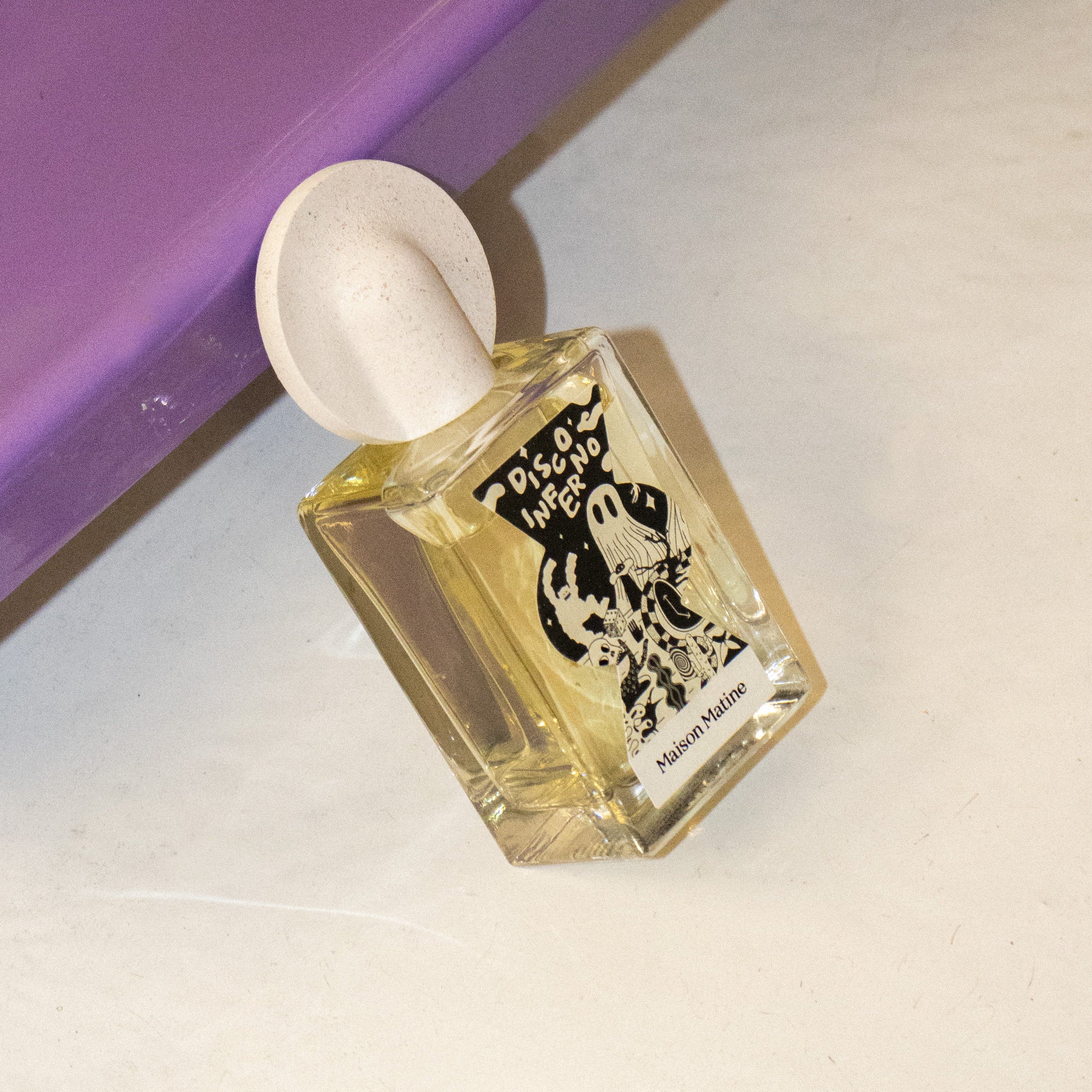 Perfume bottle with a white cap on a light surface