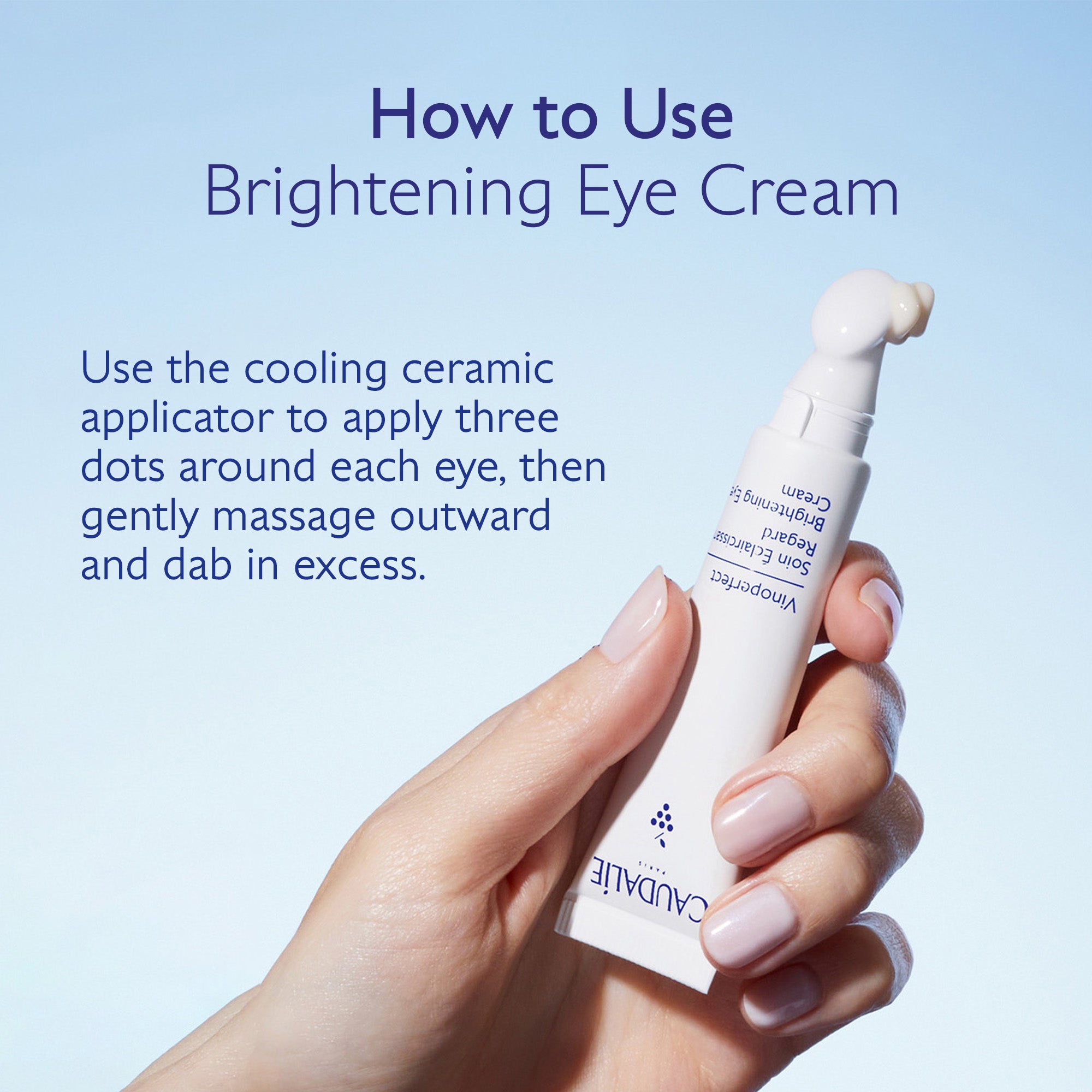 Caudalie eye cream with a hand holding it against a light blue background