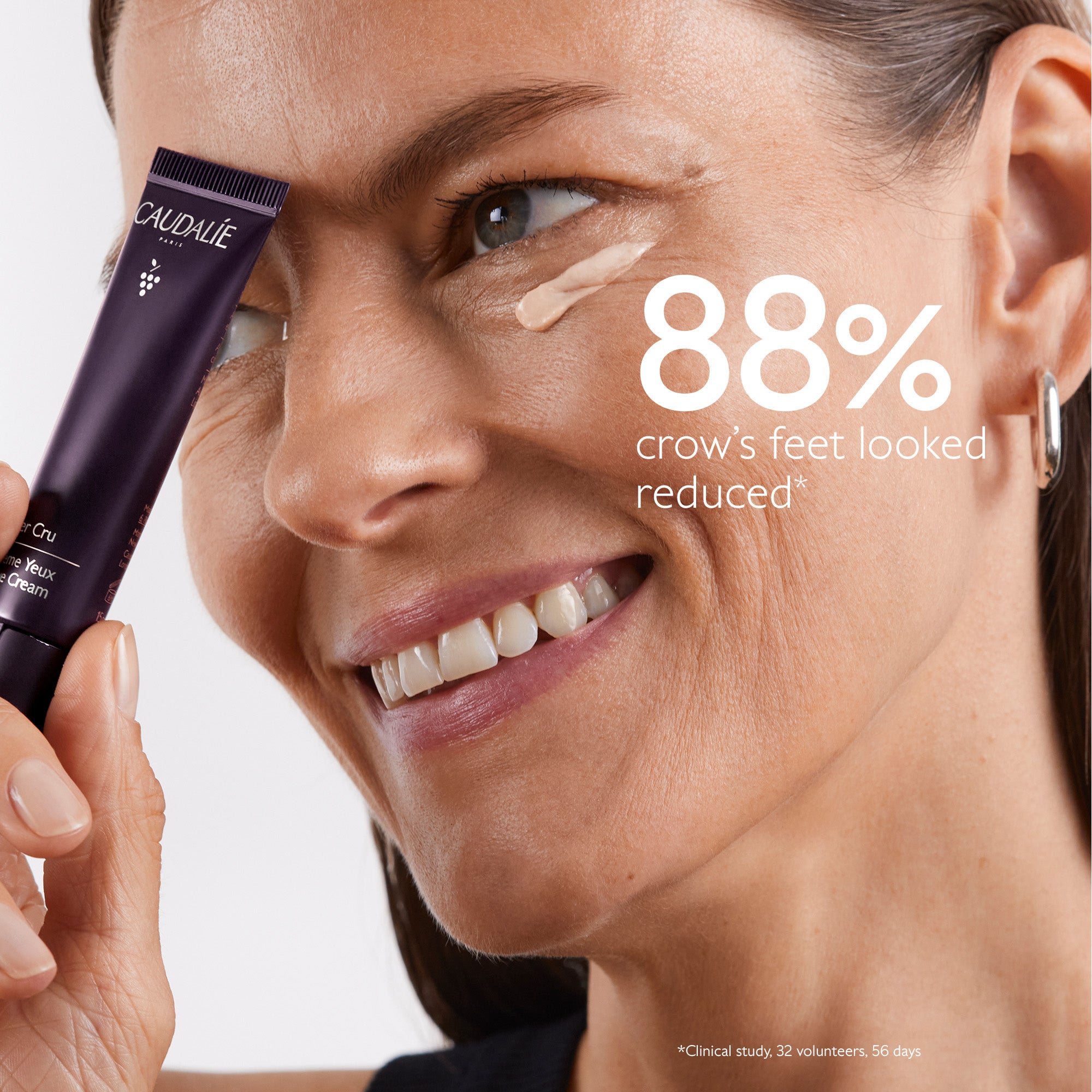 Woman applying a skincare product with visible results on crow's feet, holding a Caudéalé tube.