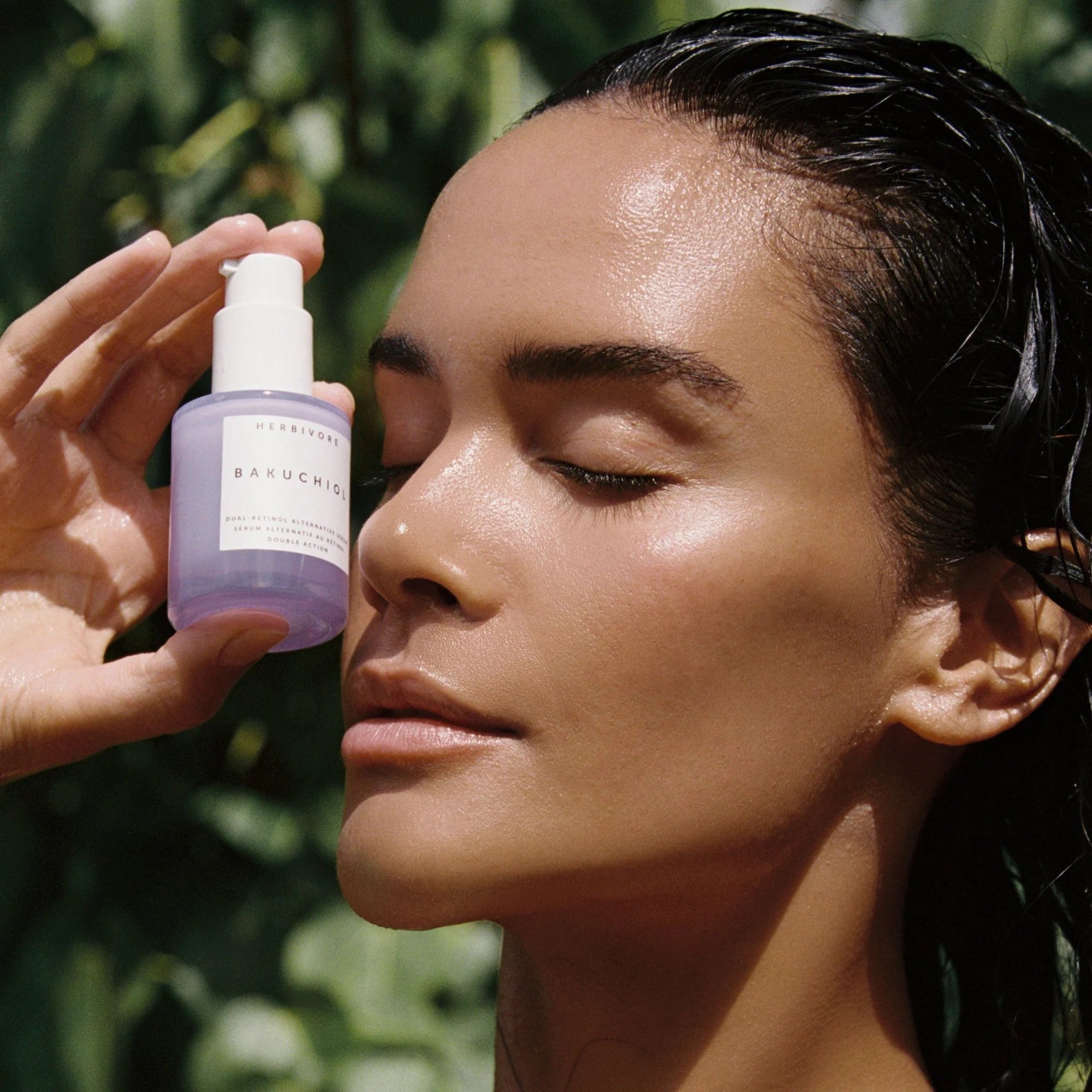 Person applying skincare product to face with greenery in the background