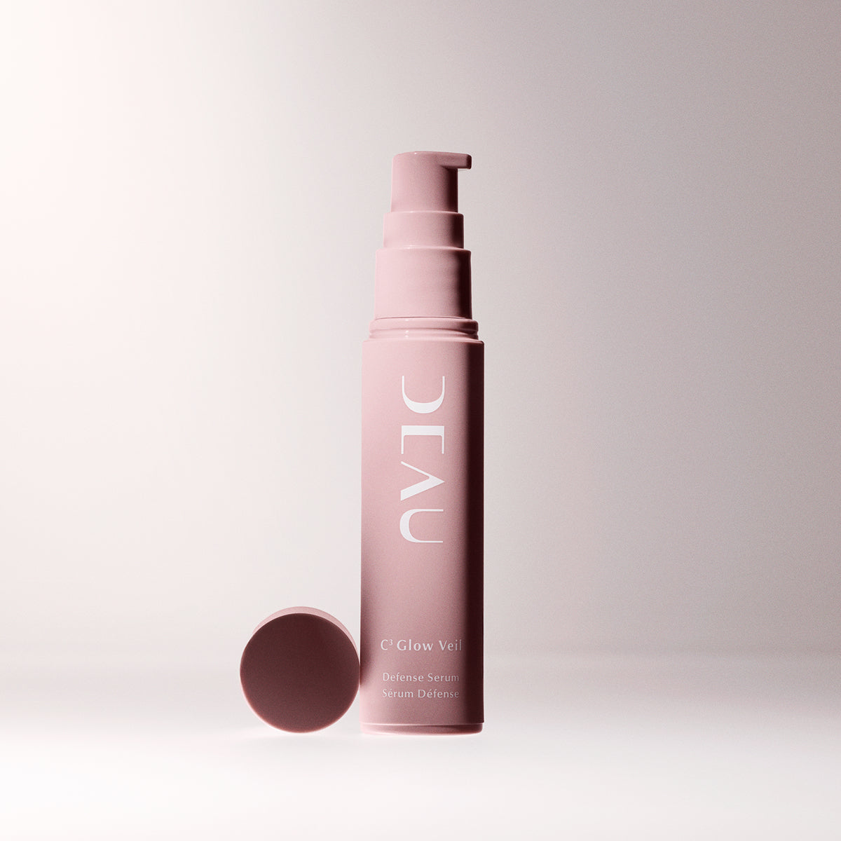 Pink skincare serum bottle with cap on a light pink background