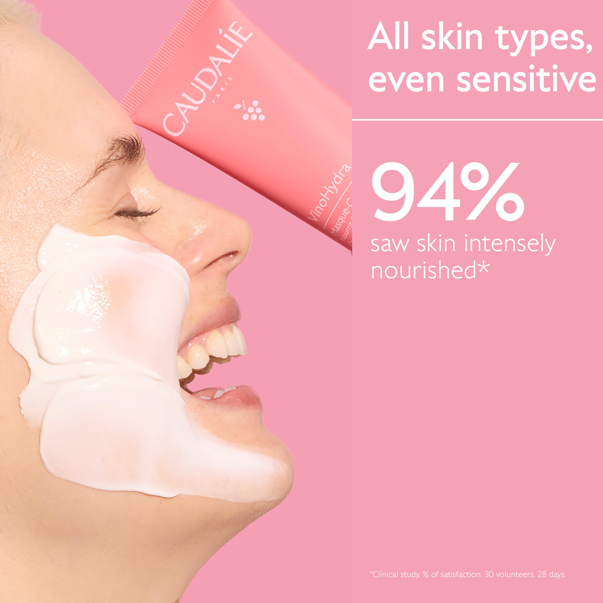 Person applying a skincare product with a pink Caudalie packet on a pink background