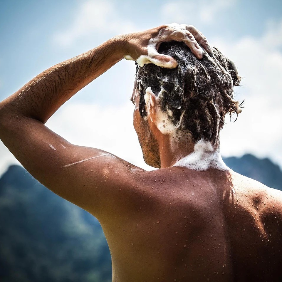 Person washing hair outdoors with mountains in the background