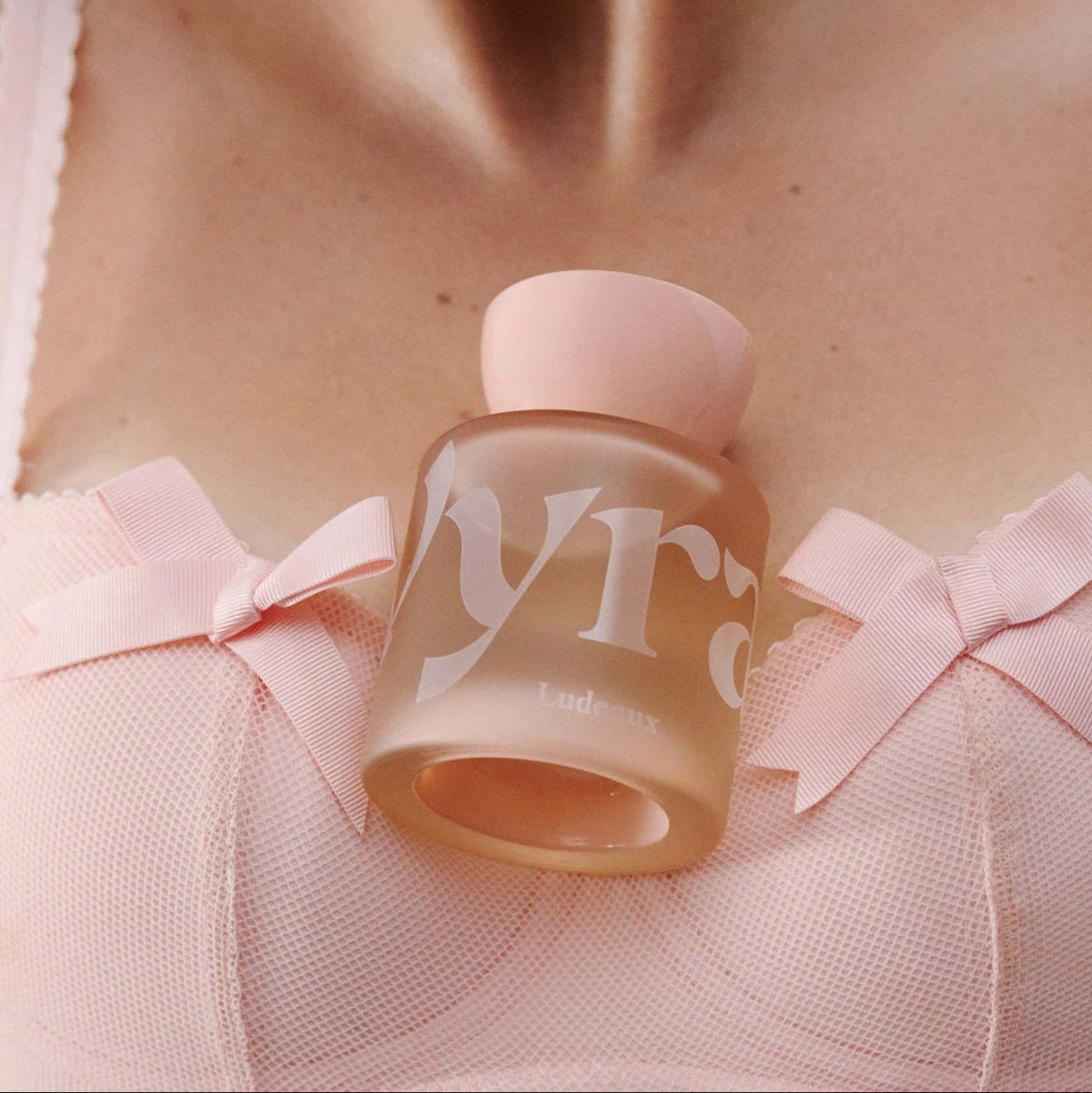 Perfume bottle with 'Vyrao' branding held by a person wearing a pink outfit.