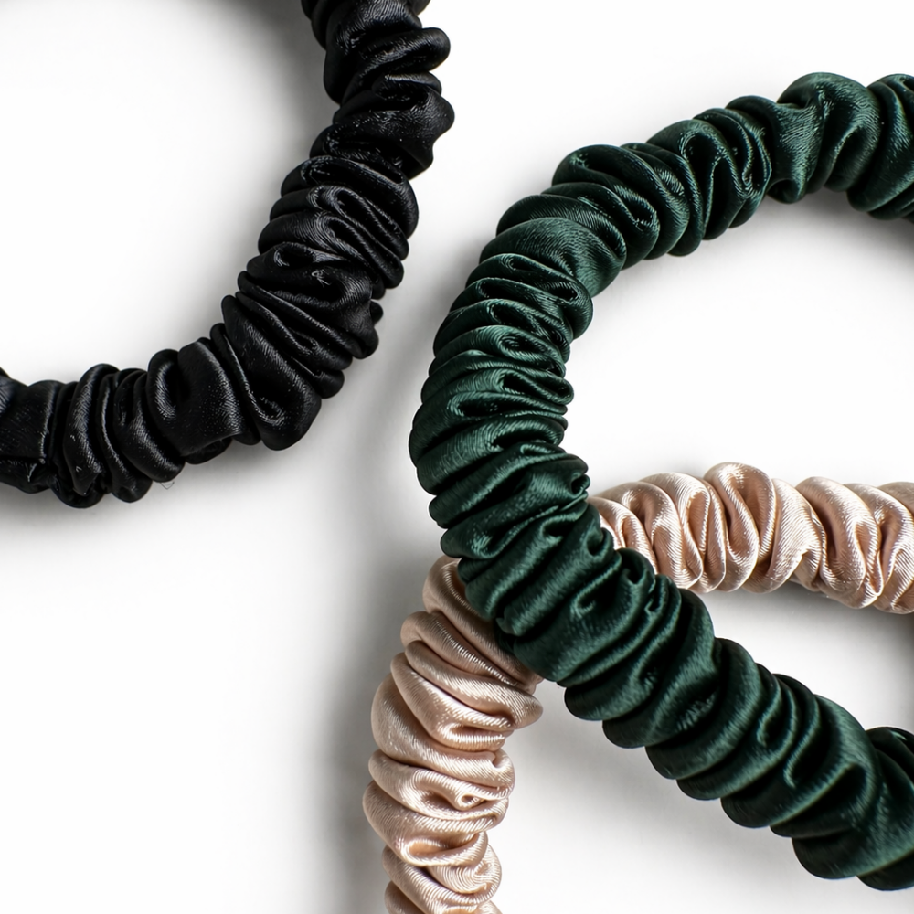 Three satin hair scrunchies in black, green, and beige on a white background