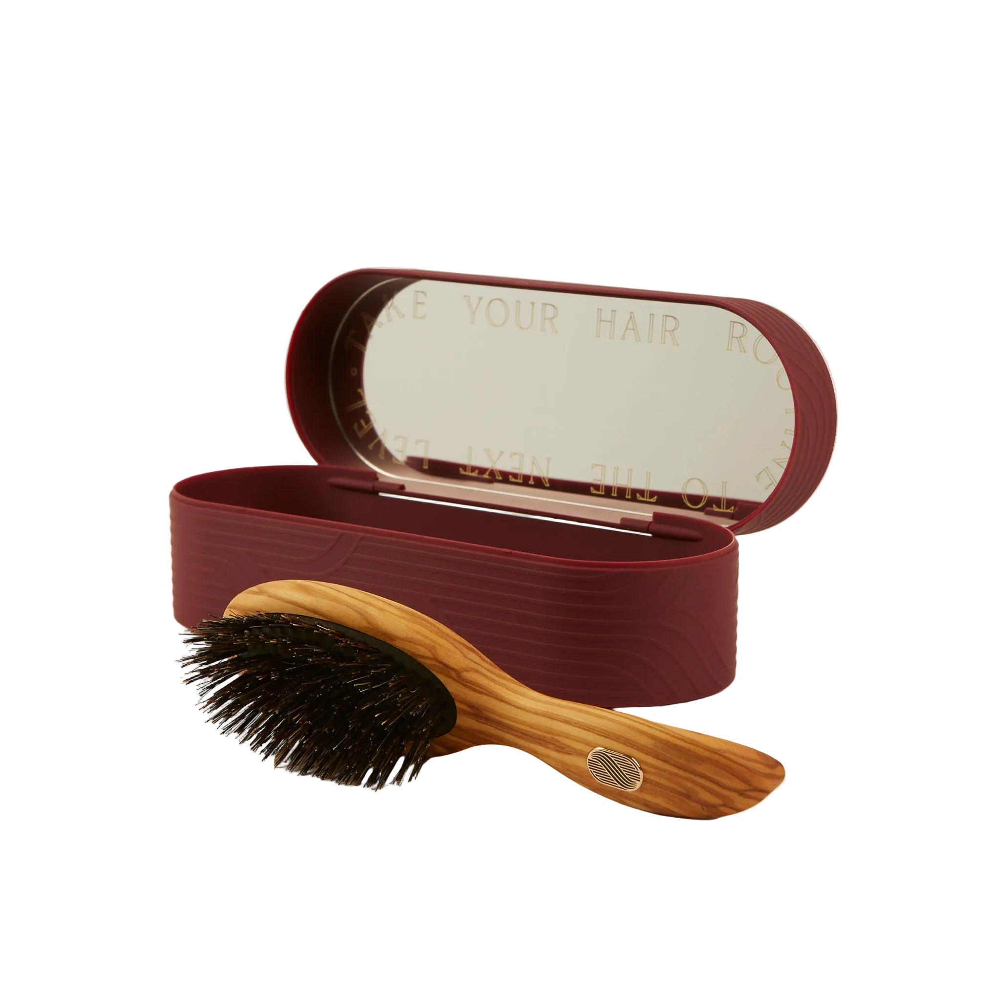 A wooden hairbrush with black bristles and a curved natural wood handle, displayed in front of its matching dark burgundy storage case with an open mirror lid, on a clean off-white background.