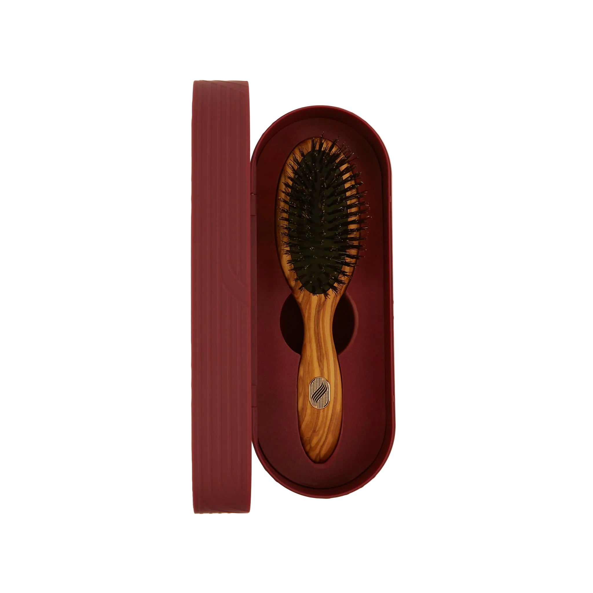 An oval hairbrush with a light wood handle and dark bristles, displayed in an open matching burgundy case next to its lid on a plain off-white background.