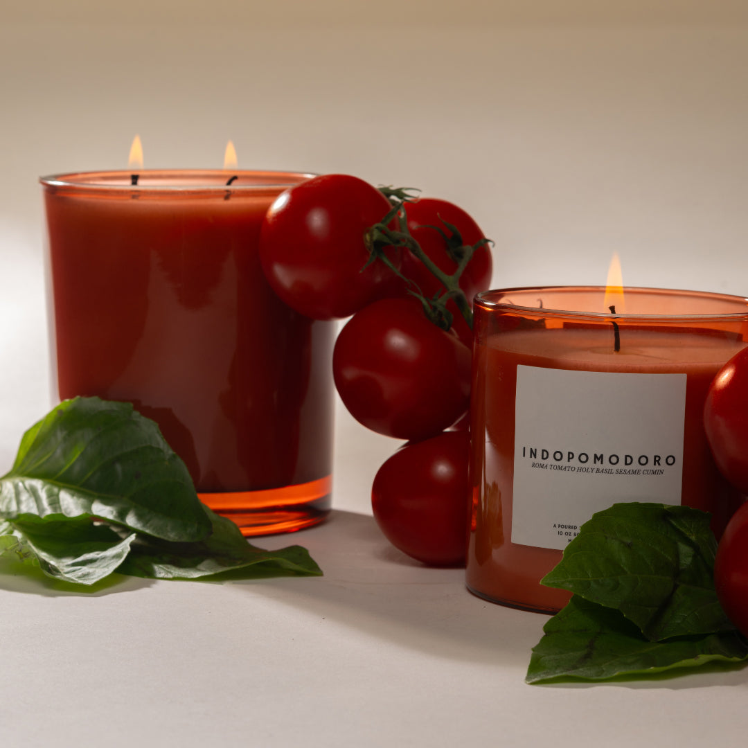 Two candles with tomatoes and leaves on a neutral background