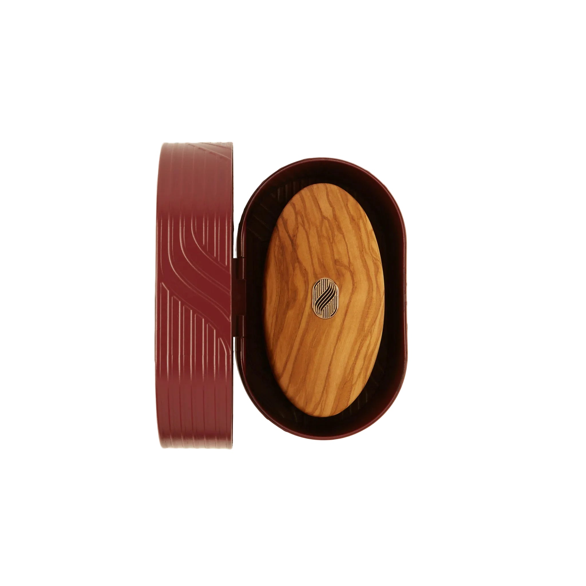An oval wooden box shown open on a light cream background, with a dark reddish-brown outer lid leaning beside it and a natural wood insert in the center featuring a small silver geometric emblem.