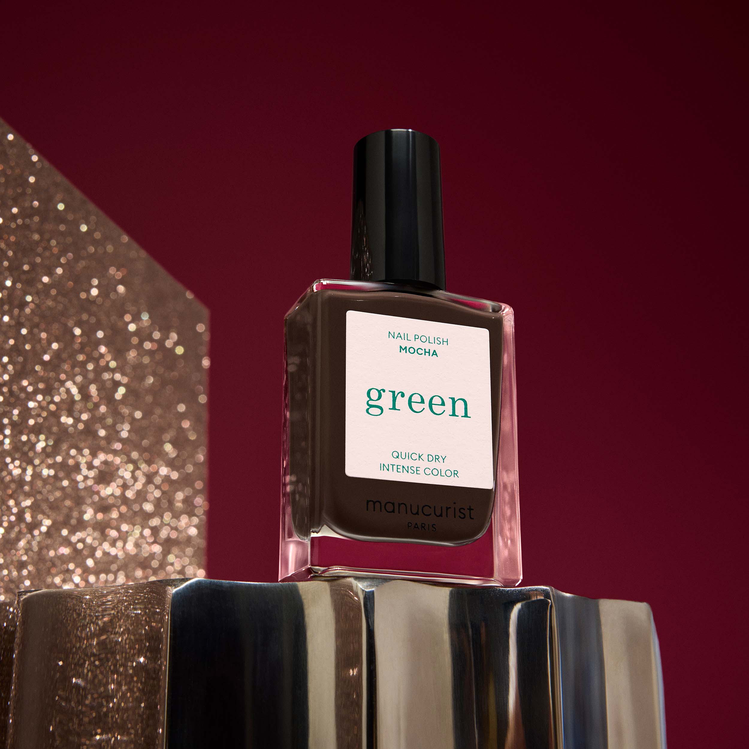 Manucurist Mocha nail polish bottle  on a metallic surface and red background