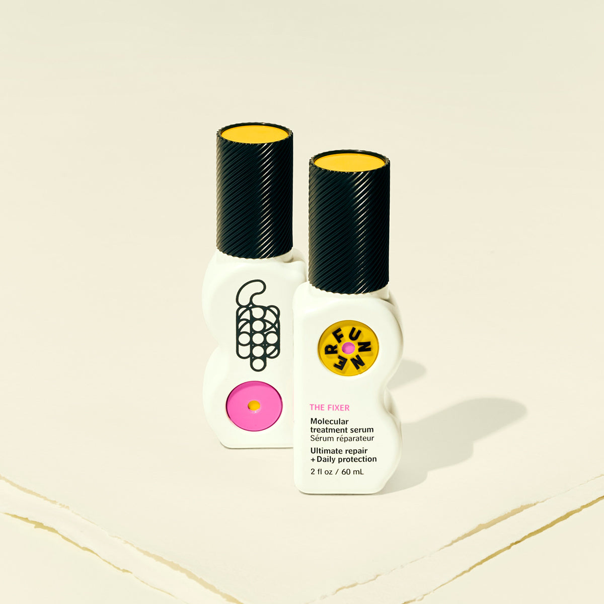 Two haircare bottles with black caps and colorful labels on a beige background