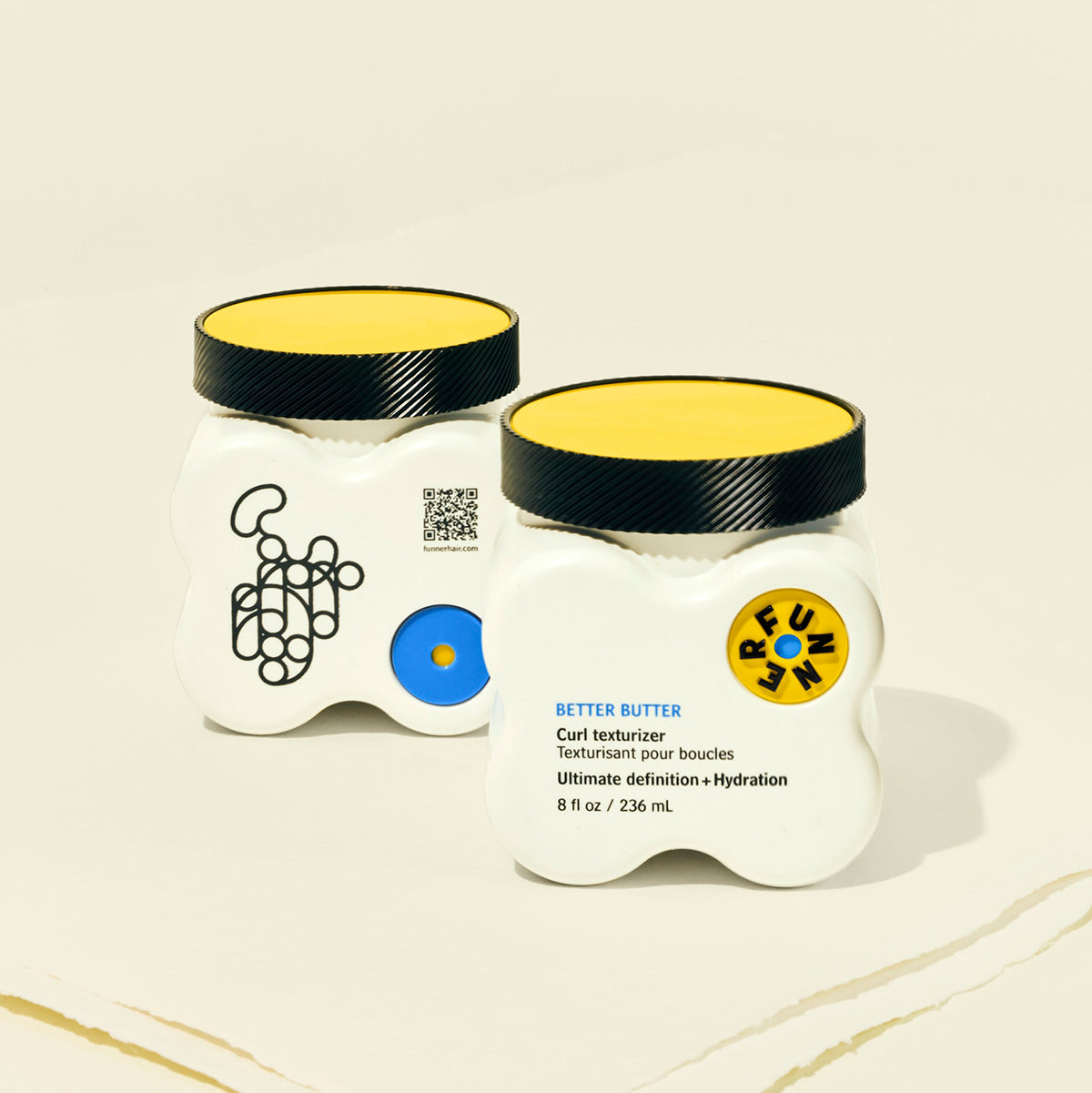 Two jars of 'Better Butter' hair product with decorative labels on a beige background