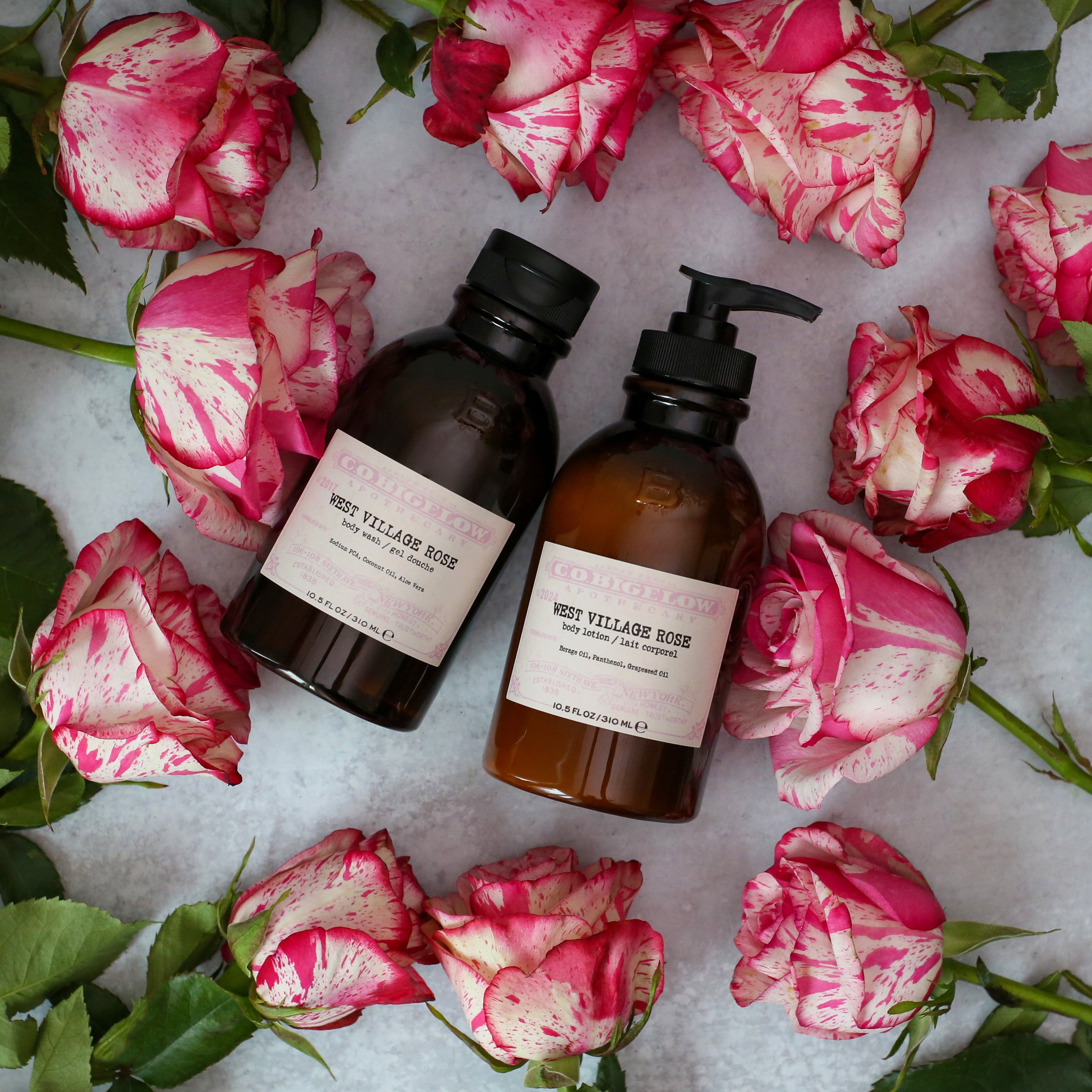 Two bottles on a white surface with pink and green flowers around them.