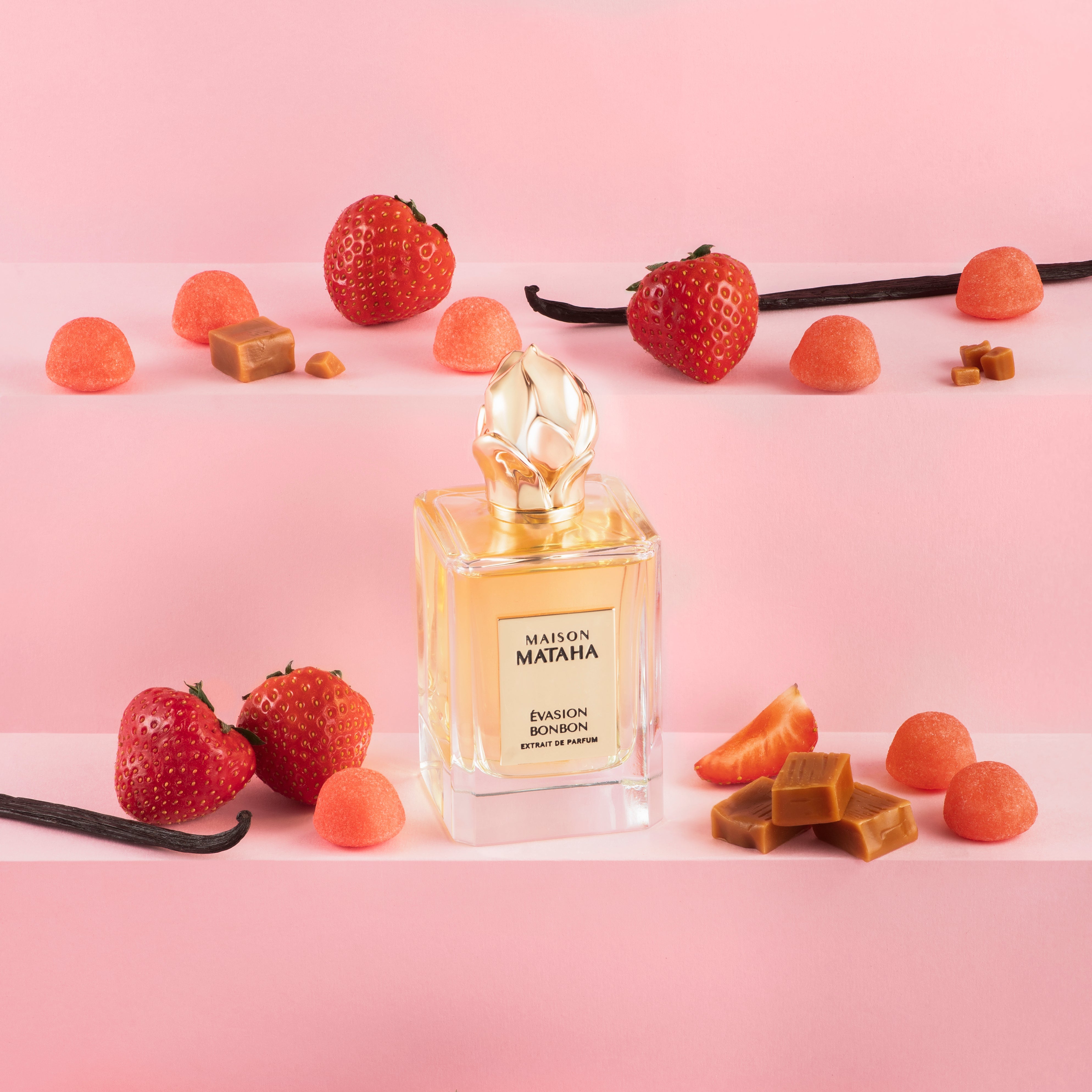 Maison Mataha perfume bottle surrounded by strawberries, vanilla and caramel on a pink background