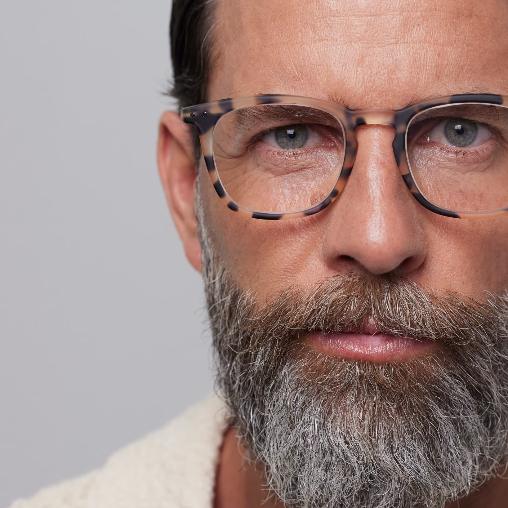 Close-up of a man wearing glasses with a neutral background