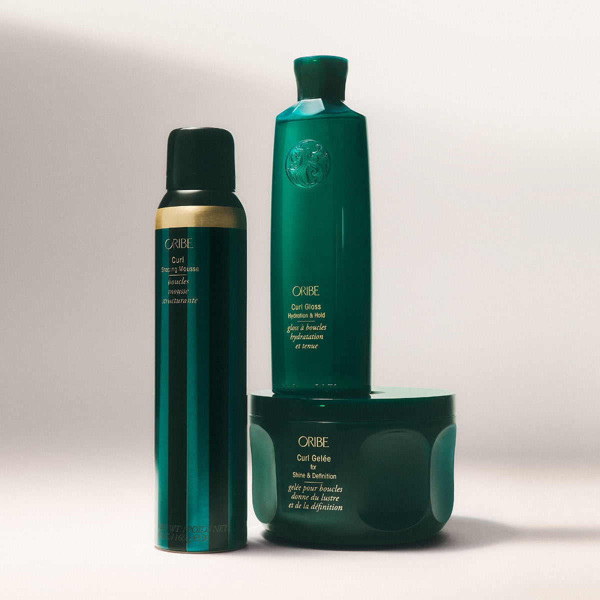 Three green hair care products from Oribe on a light gray background