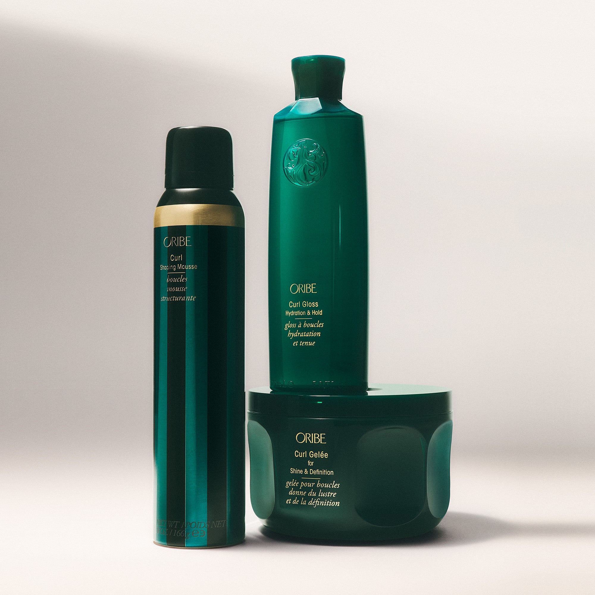 Three green hair care products from Oribe on a light gray background