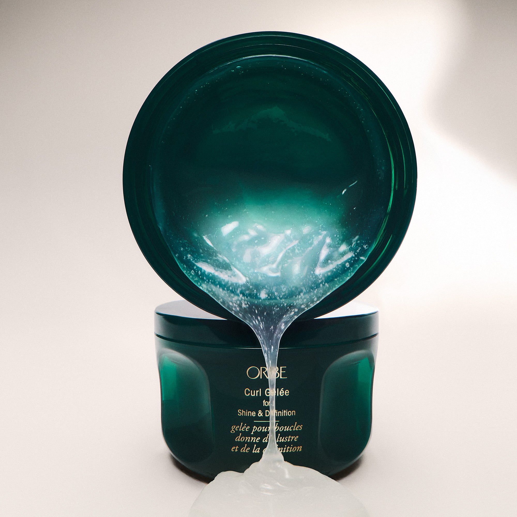 Oribe Curl Gelée hair product with open lid on a white background