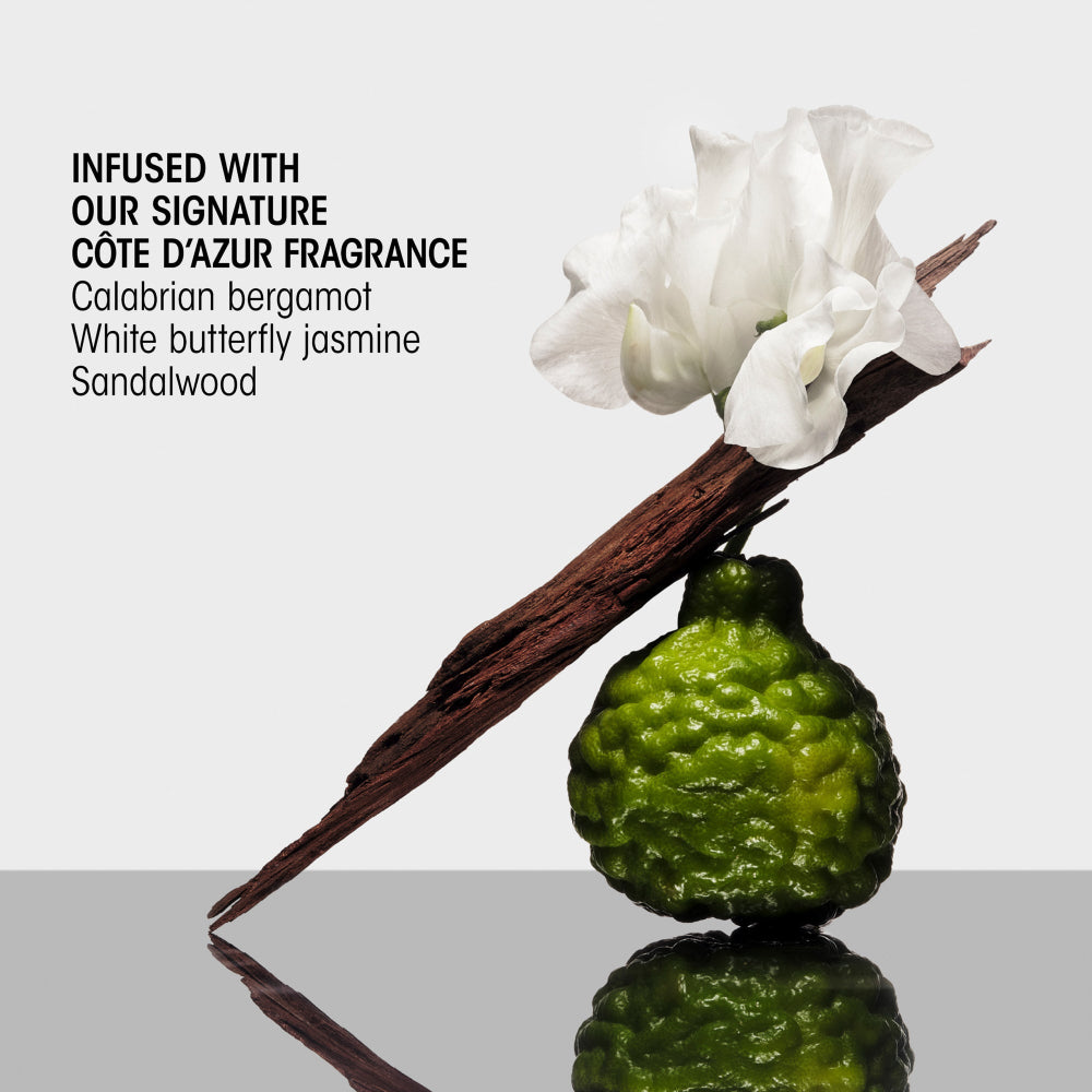 Vanilla bean, bergamot fruit, and white butterfly jasmine on a reflective surface with text about Cète d'Azur fragrance.