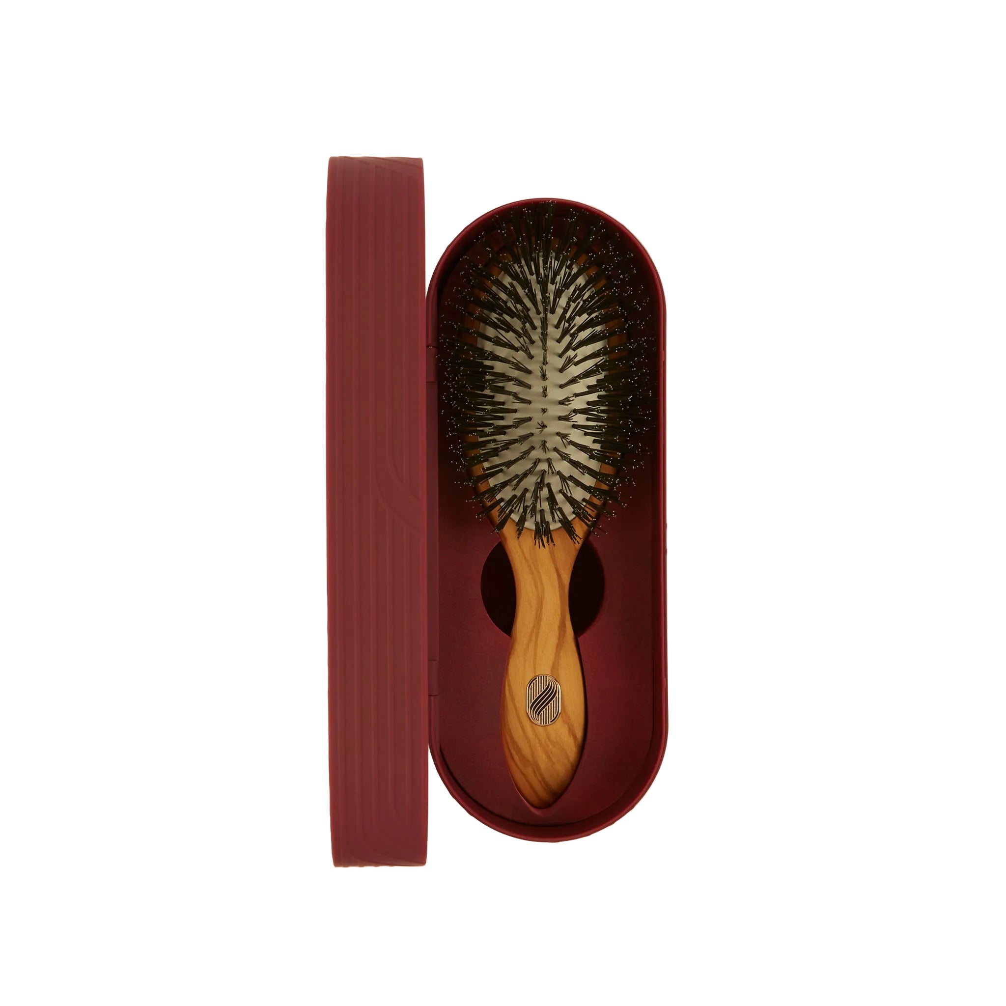 A wooden hairbrush with dark bristles and a light wood handle, presented in a matching dark burgundy oval case with its lid standing beside it on a plain light background.