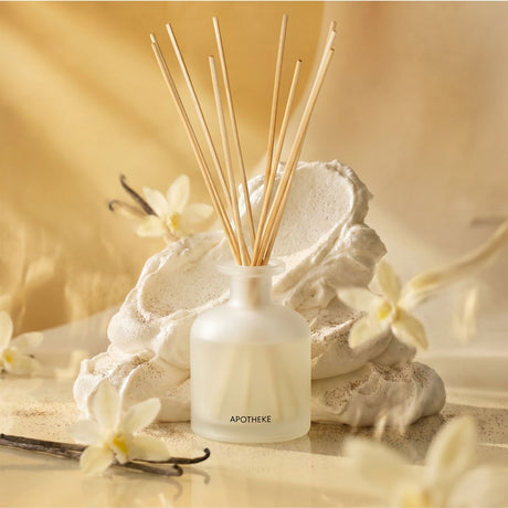 Apotheke Reed diffuser with vanilla beans and flowers on a beige background