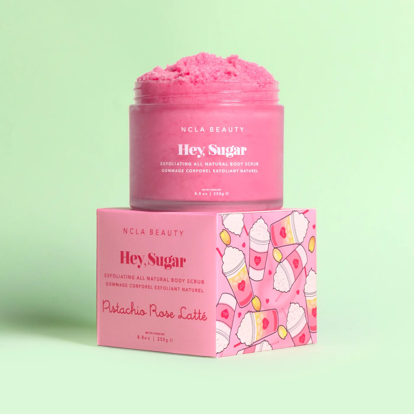 Pink body scrub jar and packaging on a light green background