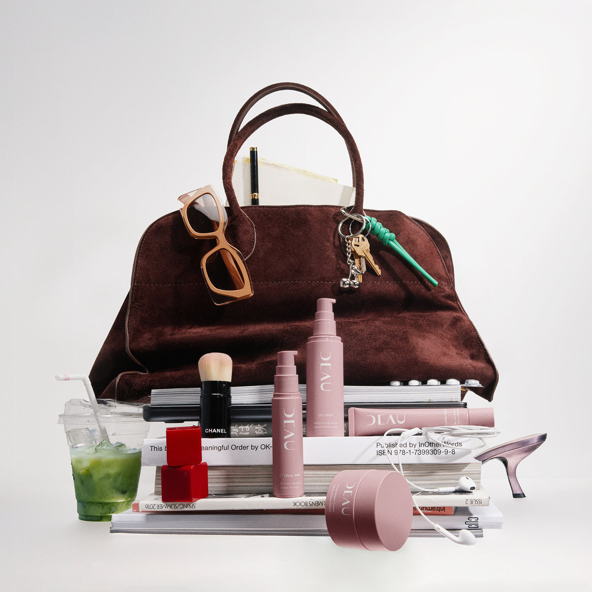 Brown handbag with cosmetic products and accessories on a white background