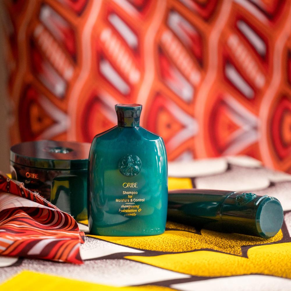 Moisture & Control Shampoo alongside other Oribe products on a orange and yellow patterned back drop 