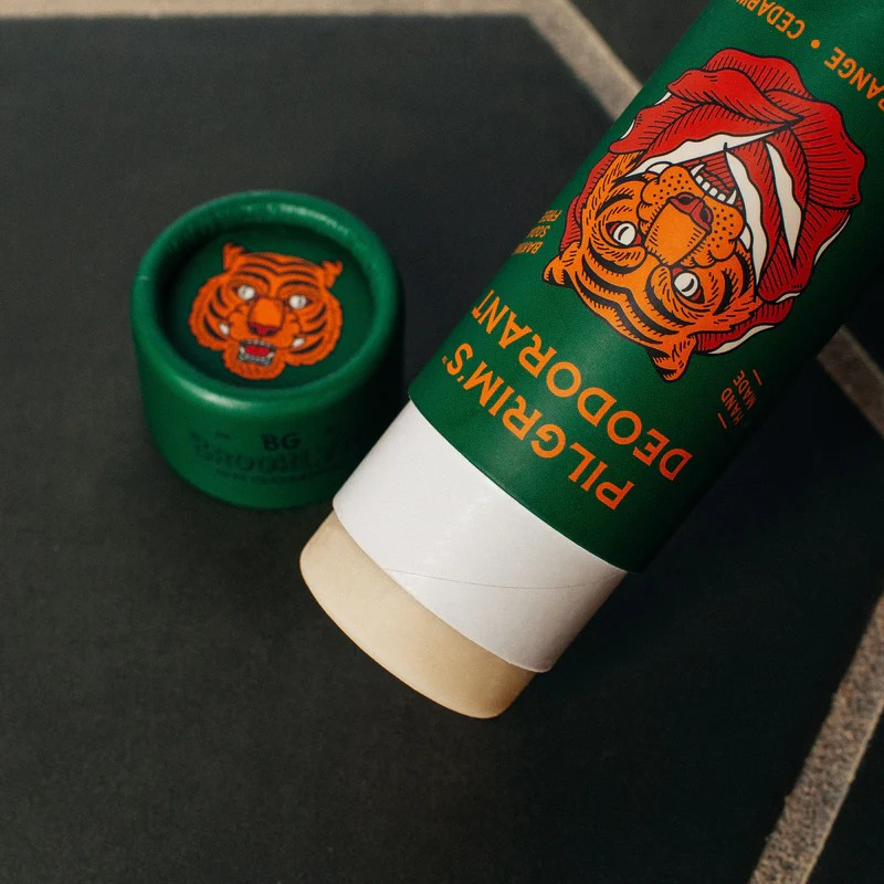 Green deodorant tube with tiger design on a dark surface