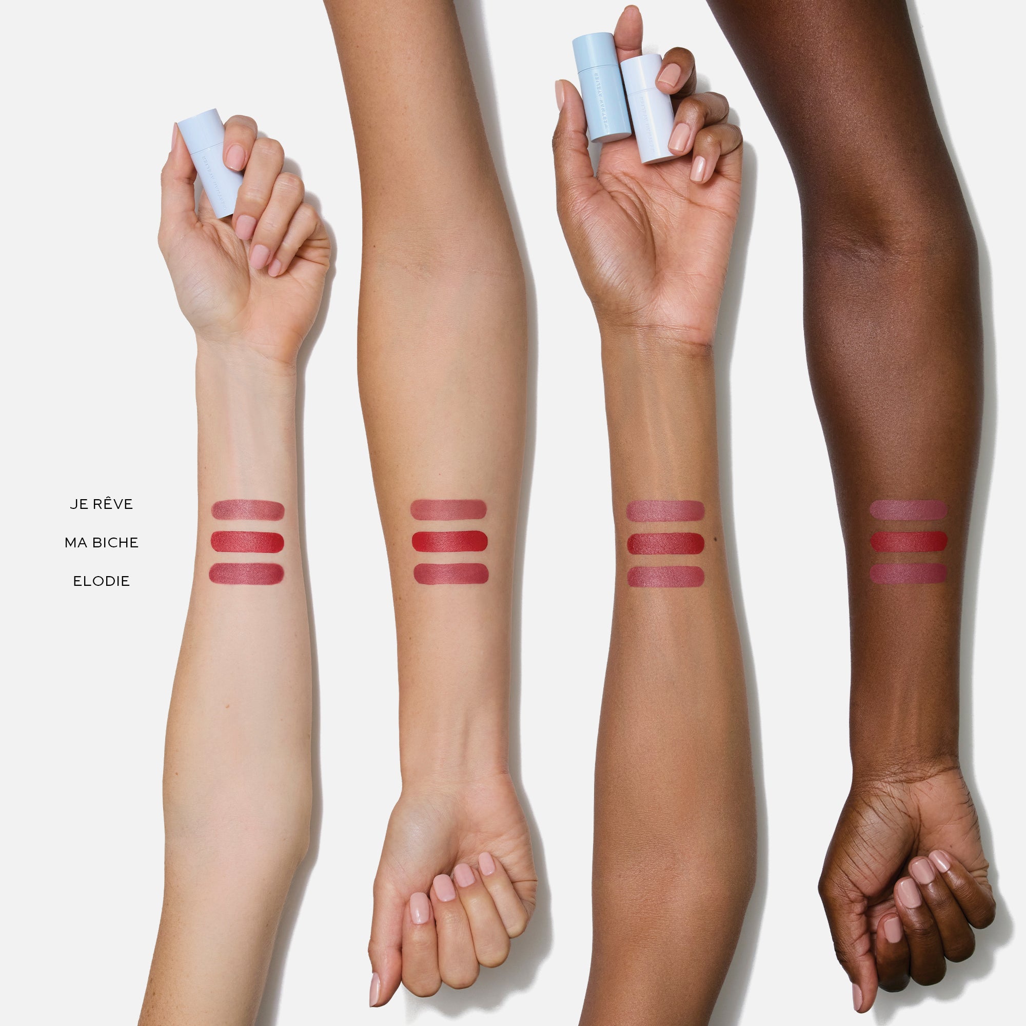 Four arms with different skin tones displaying three shades of lipstick on their forearms against a white background.