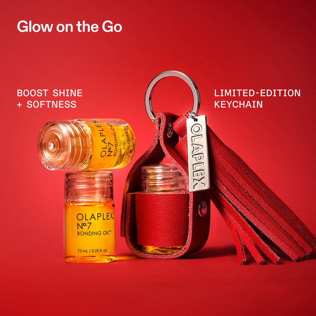 A red leather keychain pouch with a silver metal keyring and a red tassel, shown alongside two small amber glass bottles of Olaplex No. 7 Bonding Oil on a solid red background.