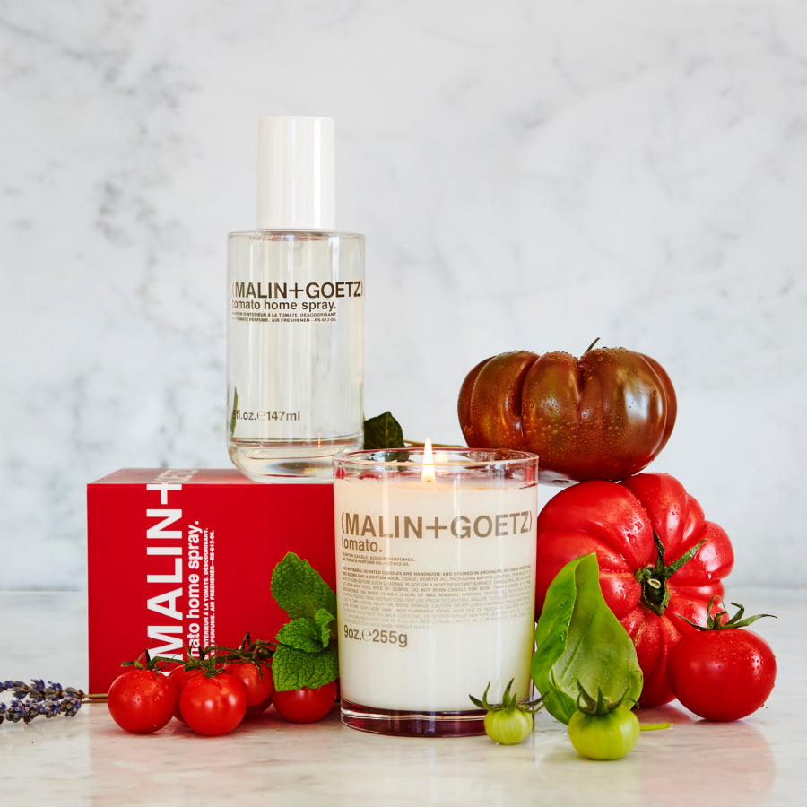 MALIN+GOETZ products including a candle and home spray with tomatoes and a box on a light background