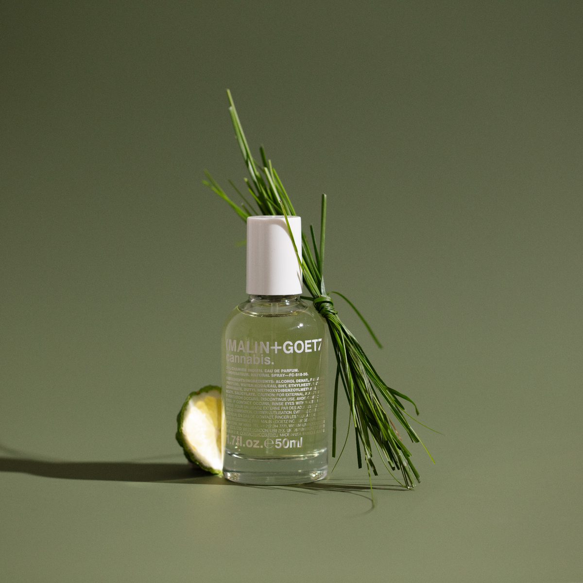 Malin + Goetz cannabis-infused eau de parfum bottle with green leaves on a green background